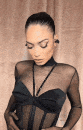 a woman wearing a black sheer top with rhinestones on it