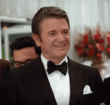 a man in a suit and bow tie is smiling .