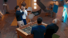 a group of men standing around a foosball table with the letters rtve on the bottom
