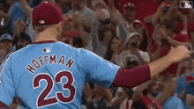 a baseball player wearing a number 23 jersey is standing in front of a crowd of people .