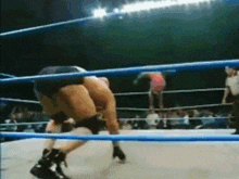 a blurry picture of two wrestlers in a ring with a referee in the background
