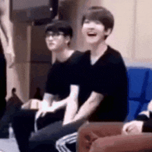 a group of people are sitting on a couch in a room laughing .