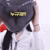 a woman is blowing up a heart shaped balloon in front of her face