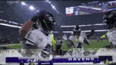 a ravens football player celebrates a touchdown in front of the scoreboard