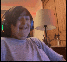 a man wearing headphones is smiling in front of a lamp in a living room