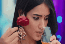 a woman with a rose on her ear is drinking from a glass