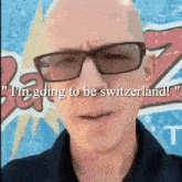 a bald man wearing glasses says " i 'm going to be switzerland ! "