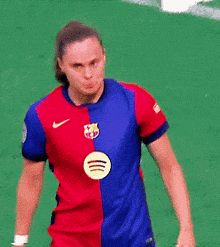 a female soccer player wearing a red and blue jersey with a yellow spotify logo on it