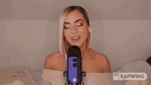 a woman is singing into a blue microphone with the words ksmr written above her