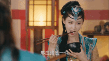 a woman in a costume is eating from a bowl with chopsticks in her mouth