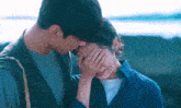 a man kisses a woman on the cheek while she covers her face with her hand