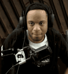 a man wearing headphones is sitting in front of a microphone and looking at the camera .