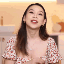 a woman wearing a floral top and earrings looks up at the camera