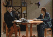 two men are sitting at a table with papers on it