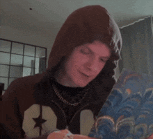a young man wearing a brown hoodie with a star on it