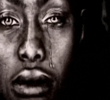 a black and white photo of a man 's face with a tear running down his cheek .