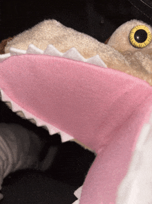a close up of a stuffed animal with pink teeth and yellow eyes
