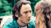 a man in a blue shirt is looking at a woman in a white shirt .