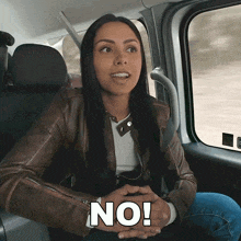 a woman in a leather jacket is sitting in the back seat of a car and says no
