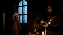 a man with a crown on his head is standing in front of a candle