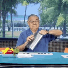 a man is sitting at a table holding a stainless steel container