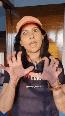 a woman wearing an orange hat is making a funny face with her hands