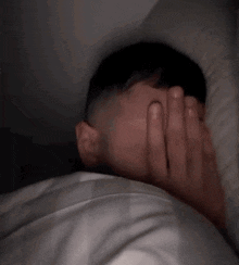 a man with a beard is covering his face with a pillow while sleeping .