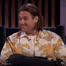 a man wearing a floral shirt is sitting in a chair on nbc songland