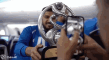 a person taking a picture of a man holding a trophy with emaar written on the bottom