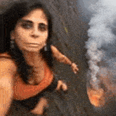 a woman is taking a selfie in front of a fire and smoke .