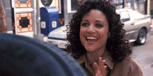 a woman with curly hair is smiling while standing in front of a parking meter with the number 8 on it
