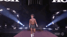 a man without a shirt is walking on a stage that says aew tnt on it