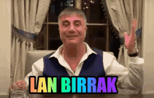 a man is sitting at a table with a glass of water and a sticker that says lan birrak