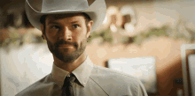 a man wearing a white cowboy hat and tie