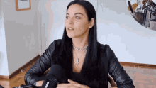 a woman wearing a shure microphone is sitting in a chair