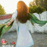 a woman in a white dress is holding a green scarf in her hand .