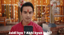 a man with a red bindi on his forehead looks at a cell phone with the words jaldi kyu abhi kyun nahi