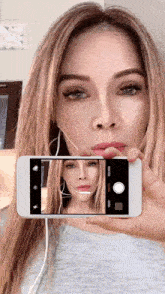 a woman taking a picture of herself with a cell phone