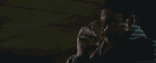 a man is holding a glass of whiskey in his hand in a dark room .