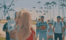 a woman in a red tank top with the letter e on it is standing next to a man holding a sign .