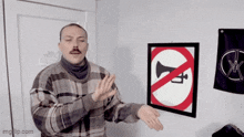 a man in a plaid sweater is standing in front of a no horn sign