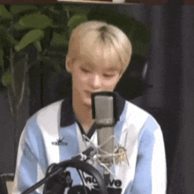 a young man is sitting in front of a microphone and talking into it .