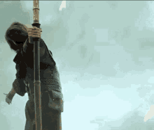 a man is holding a pole with flames coming out of it in the background