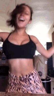 a woman in a crop top and leopard print shorts is dancing .