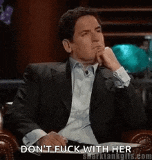a man in a suit is sitting in a chair with his hand on his chin and says `` do n't fuck with her ''