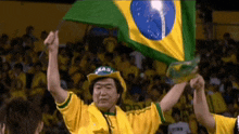 a man wearing a hat that says brasil holds up a flag