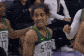 a female basketball player wearing a green and yellow uniform with the word storm on it