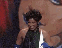 a woman in a black dress and blue gloves is smiling