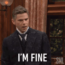 a man in a suit and tie is standing in front of a window with snl written on the bottom right