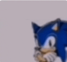 a close up of a blue sonic the hedgehog covering his face with his hand .